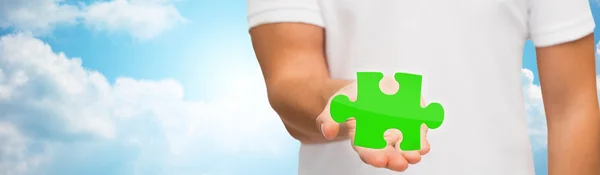 Man holding green puzzle over sky background — Zdjęcie stockowe