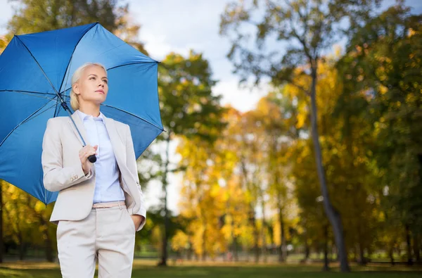 Businesswoman with umbrella over autumn background — Stock Photo, Image
