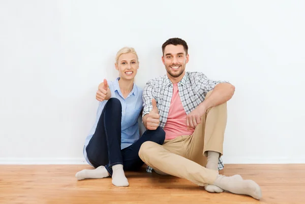 Casal feliz mostrando polegares para cima em nova casa — Fotografia de Stock