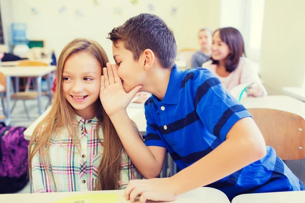 Sourire écolier chuchotant à l'oreille camarade de classe — Photo