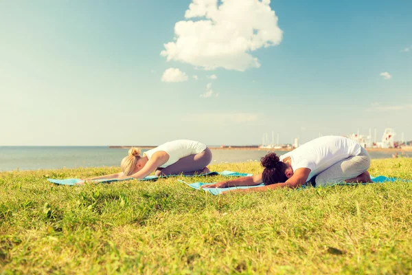 Casal fazendo exercícios de ioga ao ar livre — Fotografia de Stock