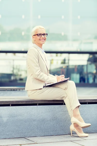 Joven mujer de negocios sonriente con bloc de notas al aire libre —  Fotos de Stock