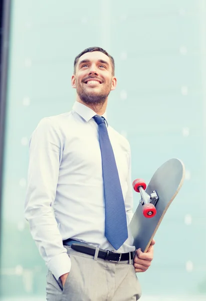 Jonge lachende zakenman met skateboard buitenshuis — Stockfoto