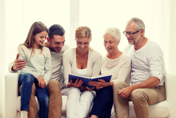 Familia feliz con libro o álbum de fotos en casa — Foto de Stock