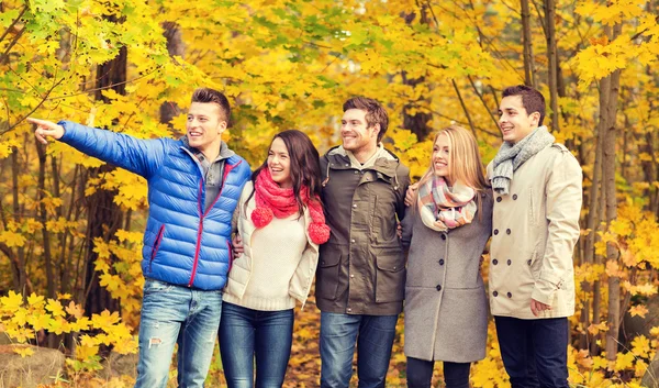 Group of smiling men and women in autumn park — Stock Photo, Image