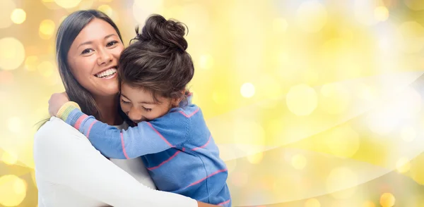 Happy mother and daughter hugging over lights — Stock Photo, Image