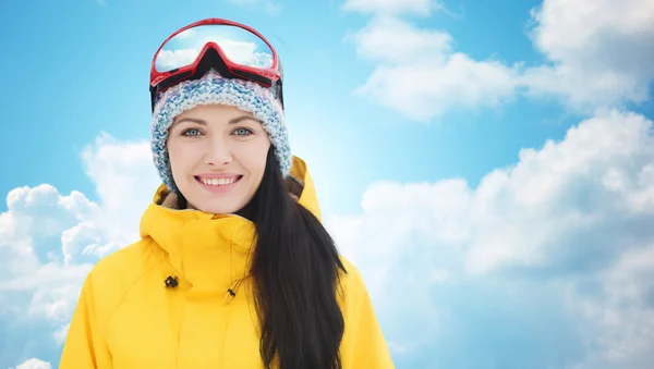 Gelukkig jonge vrouw in ski goggles over blauwe hemel — Stockfoto