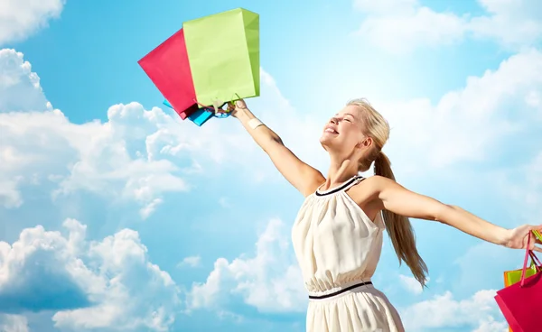 Smiling woman with shopping bag rising hands — Stock Photo, Image