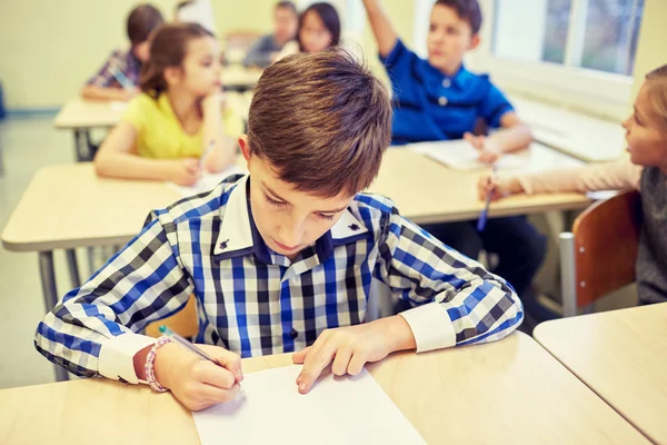 Group of school kids writing test in classroom Stock Picture