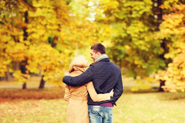 Улыбающаяся пара обнимается в осеннем парке со спины — стоковое фото