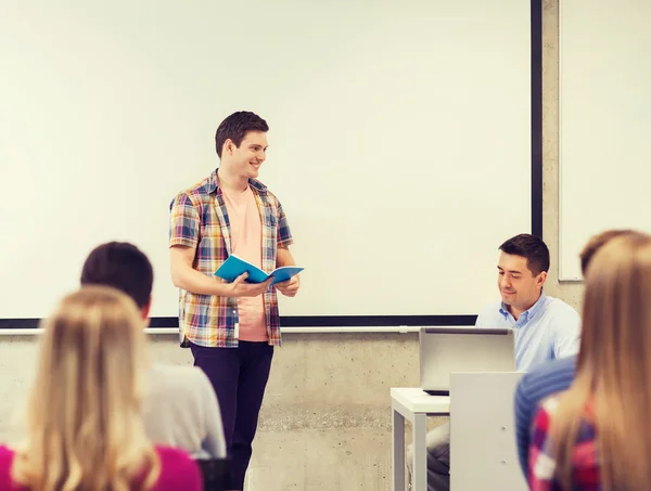 Groep glimlachend studenten en leraar in de klas — Stockfoto