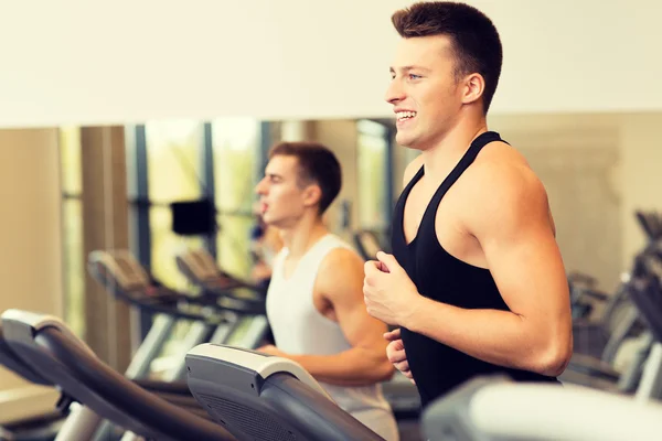 Lachende mannen uitoefenen op loopband in de sportschool — Stockfoto