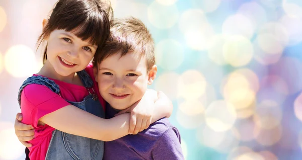 Twee gelukkige jonge geitjes knuffelen blauwe lichten achtergrond — Stockfoto