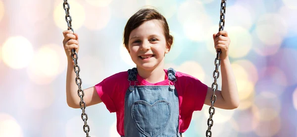 Feliz niña balanceándose en columpio sobre luces — Foto de Stock