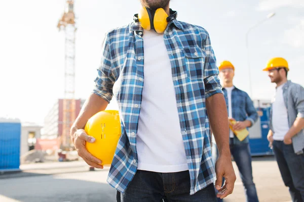 Primo piano del costruttore che tiene hardhat all'edificio — Foto Stock