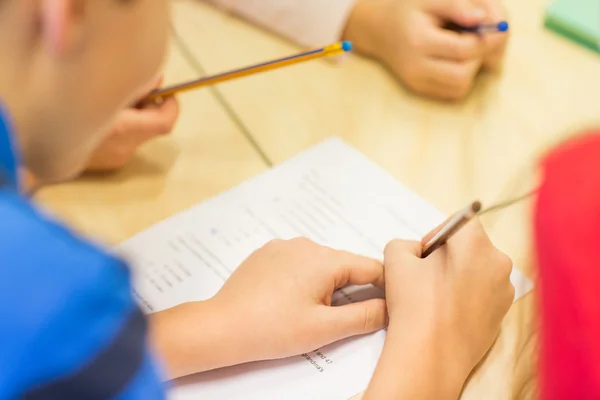Close up of schoolboy writing test at school — Stock Photo, Image