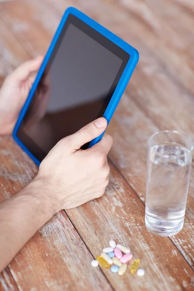 Perto de mãos com tablet pc, comprimidos e água — Fotografia de Stock