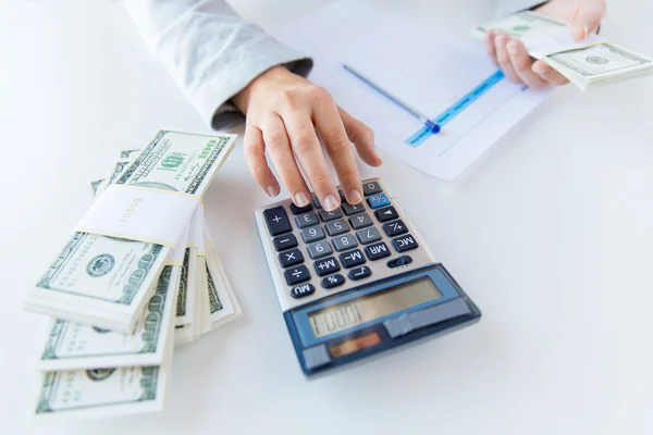 Fechar as mãos contando dinheiro com calculadora — Fotografia de Stock