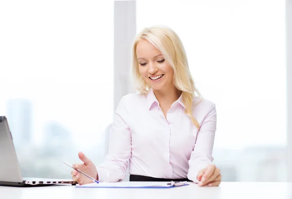 Smiling businesswoman reading papers in office Stock Photo