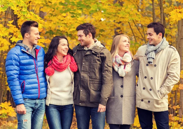 Группа улыбающихся мужчин и женщин в осеннем парке — стоковое фото
