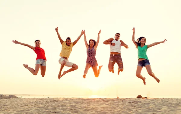 Amigos sonrientes bailando y saltando en la playa — Foto de Stock