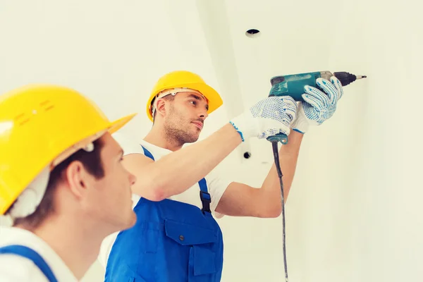 Group of builders with drill indoors — Stock Photo, Image