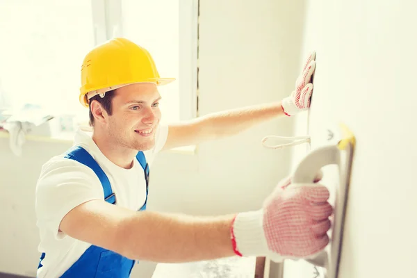 Construtor sorrindo com ferramenta de moagem dentro de casa — Fotografia de Stock