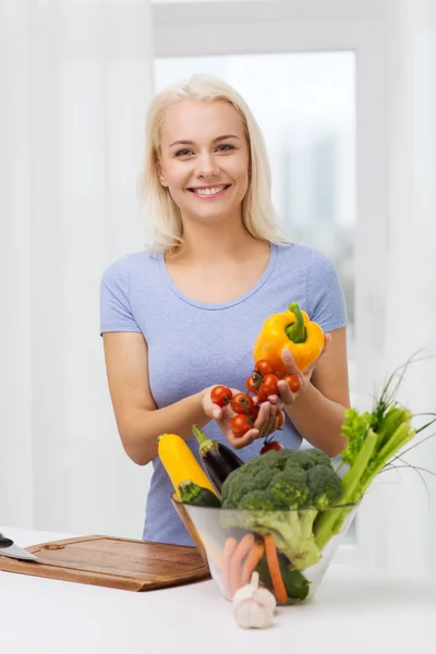 若い女性が自宅に野菜を料理を笑顔 — ストック写真