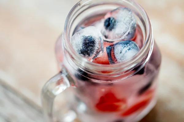 Close up of fruit water in glass mug on table — Stock Fotó