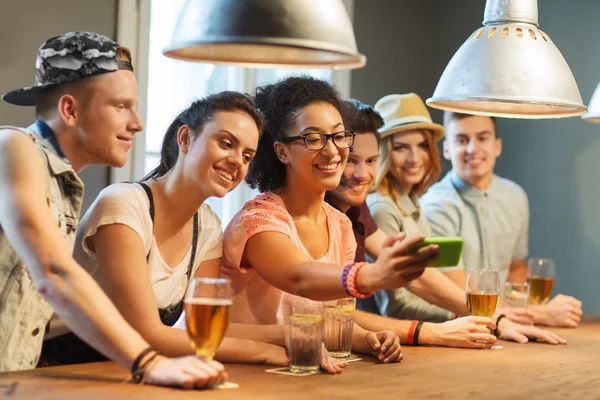 Amigos felizes com smartphone tomando selfie no bar — Fotografia de Stock