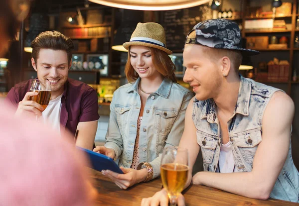 Счастливые друзья с планшетным компьютером и напитками в баре — стоковое фото