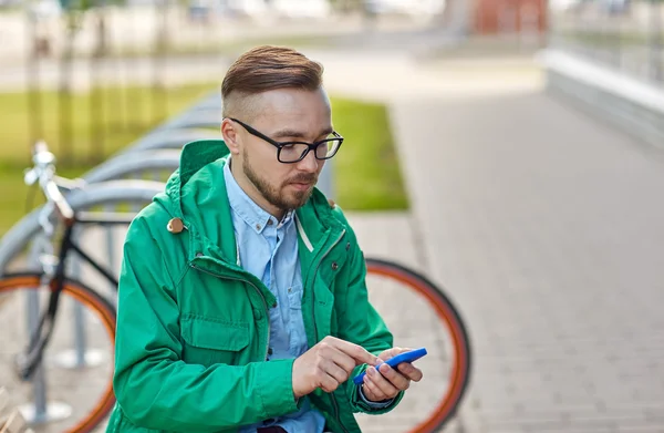 Joven hipster hombre con teléfono inteligente y byke — Foto de Stock