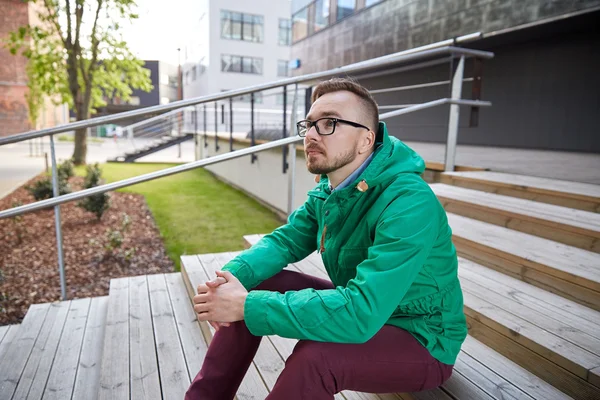 Χαρούμενος νεαρός hipster ανθρώπου πού κάθεται στις σκάλες στην πόλη — Φωτογραφία Αρχείου