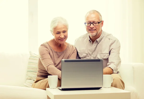 Feliz casal sênior com laptop e copos em casa — Fotografia de Stock