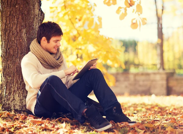 Tablet pc sonbahar Park ile genç adam gülümsüyor — Stok fotoğraf