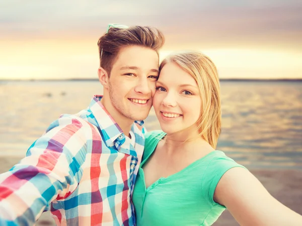 Coppia sorridente con smartphone sulla spiaggia estiva — Foto Stock