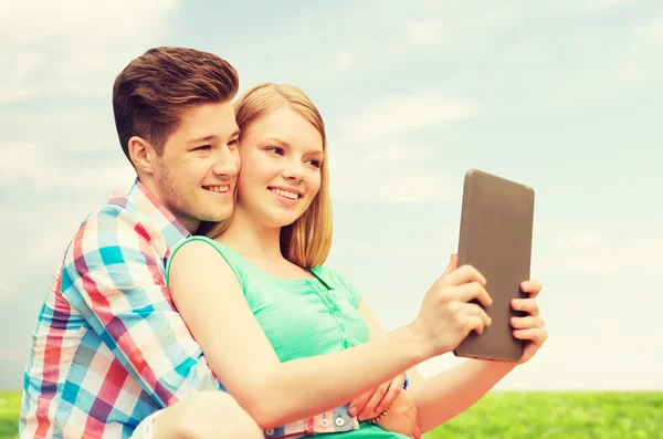 Casal feliz com tablet pc tomando selfie ao ar livre — Fotografia de Stock