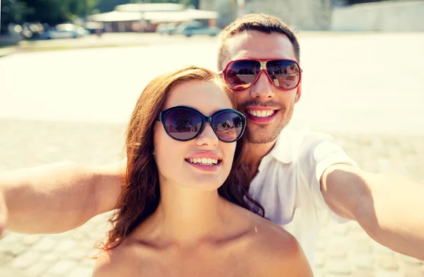 Sorrindo casal usando óculos de sol fazendo selfie — Fotografia de Stock