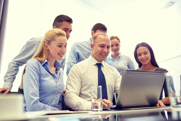 Χαμογελώντας επιχειρηματίες με φορητό υπολογιστή στο γραφείο — Φωτογραφία Αρχείου