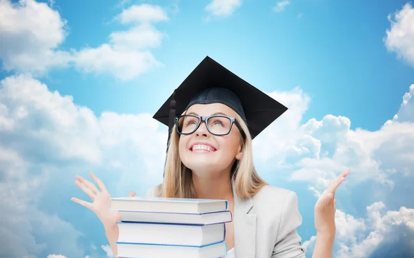 Menina estudante feliz em boné de solteiro com livros — Fotografia de Stock