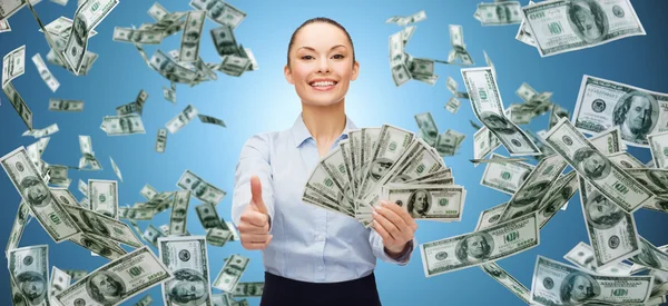 Smiling businesswoman with money showing thumbs up — Stockfoto