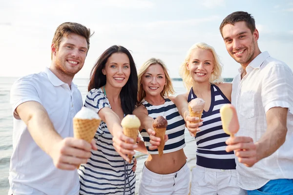 Amigos sonrientes comiendo helado en la playa — Foto de Stock