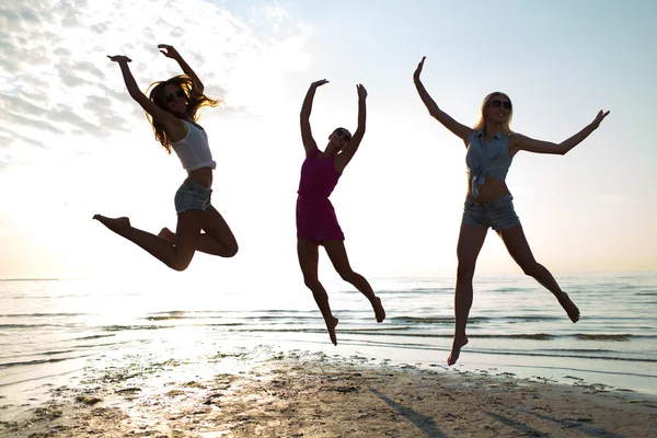 Glückliche Freundinnen tanzen und springen am Strand — Stockfoto