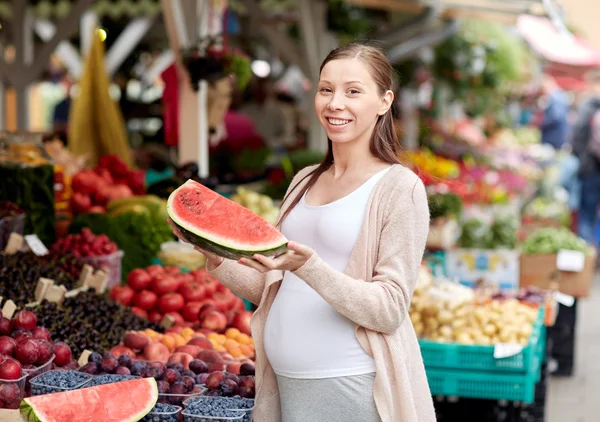 Mujer embarazada sosteniendo sandía en el mercado callejero — Foto de Stock