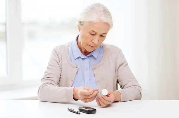 Старша жінка з глюкометром перевіряє рівень цукру в крові — стокове фото