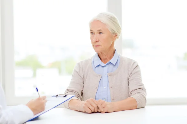 Arzt mit Klemmbrett und Seniorin im Krankenhaus — Stockfoto