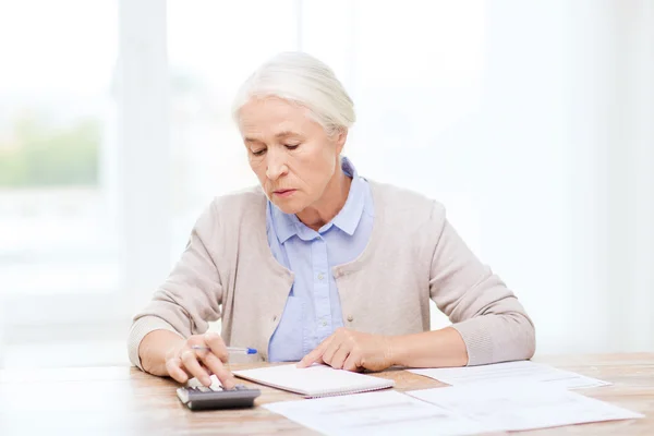 Seniorin mit Papieren und Taschenrechner zu Hause — Stockfoto