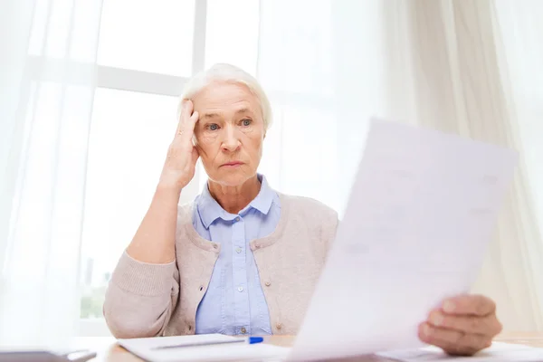 Senior woman with papers and calculator at home — Stock Photo, Image