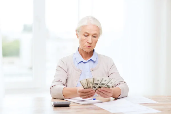 Senior femme avec de l'argent et des papiers à la maison — Photo