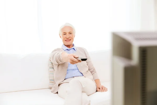 Happy senior woman watching tv at home — Stock Photo, Image